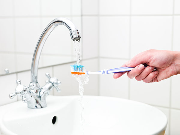 A person rinsing their toothbrush, the best way for cleaning your toothbrush 