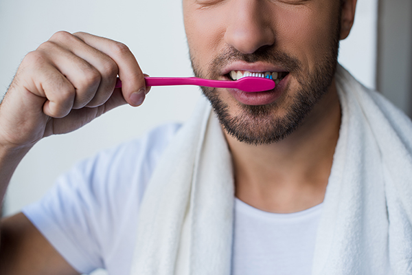 A man brushing his teeth to enjoy the benefits of healthy teeth and gums.