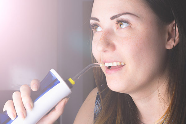 A woman using a water flosser