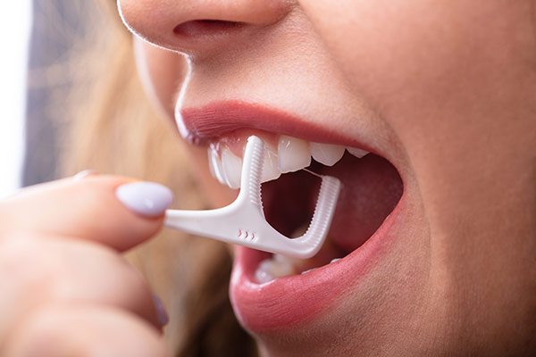 A woman using a dental floss pick