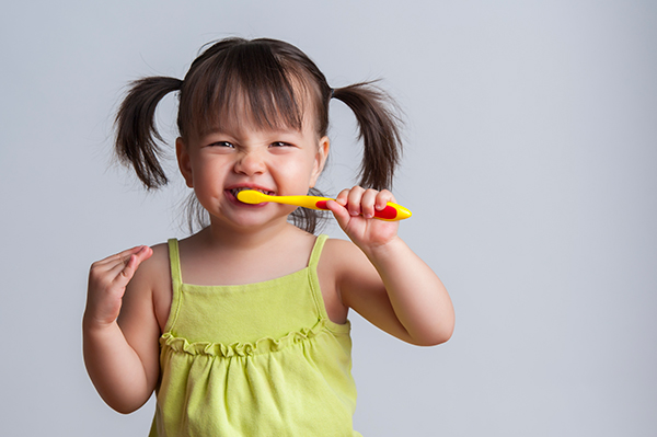 A child brushing her teeth & demonstrating good dental care.
