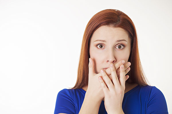 A woman covering her mouth due to not having fresh breath.