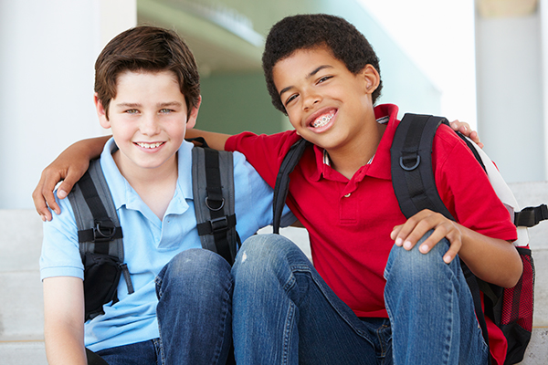 A child without braces and a child with braces smiling before school. 