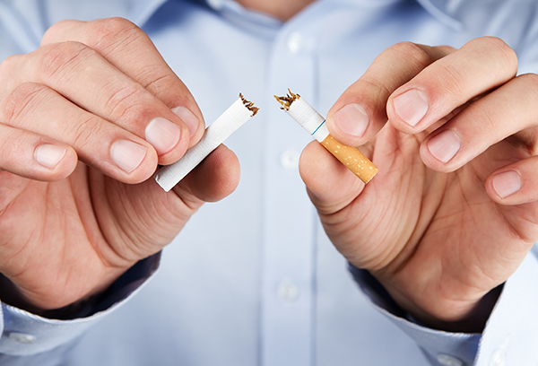 A smoker breaking his cigarette due to the effects of smoking on oral health