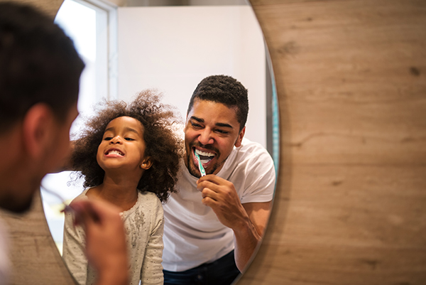 A father teaching dental care to their child.