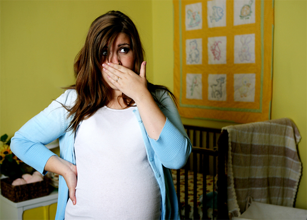 Pregnant woman holding her hand over her mouth - pregnancy gingivitis