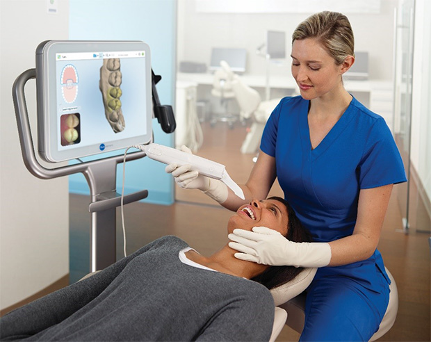 A dental technician uses the iTero® impressionless dental mouth scanners on a smiling patient.