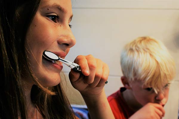 A young girl and young boy brush their teeth with manual toothbrushes | Dental apps for kids