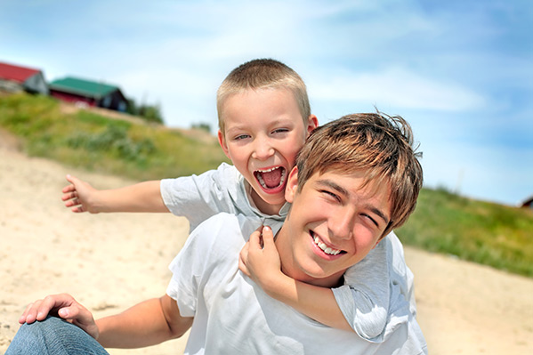 Smiling teenage boy and younger brother playing together on vacation | Travel Dental Kit