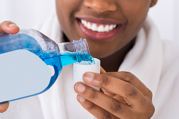 Woman pouring blue mouthwash into the cap to reduce dry mouth
