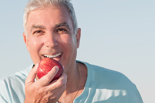 Smiling senior man holding an apple.