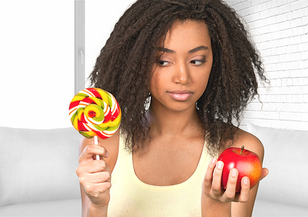 Why it's hard to avoid eating sugar - Woman holding an apple and large lollypop in her hands.