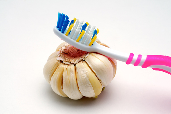 Clove of garlic with a toothbrush resting on top.