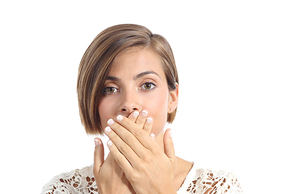 Woman with bad breath covering her mouth.