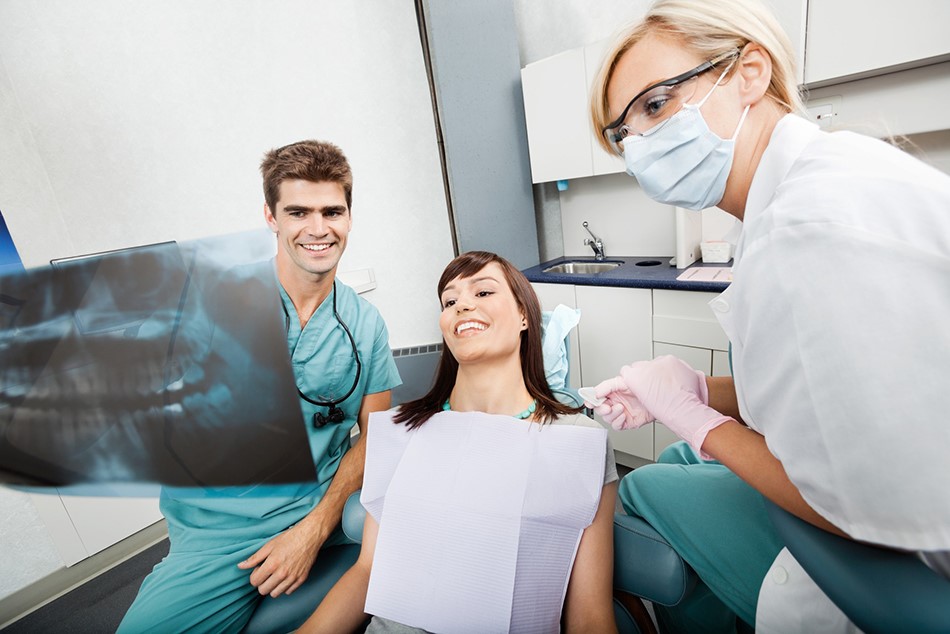 Dentist and hygienist looking at panoramic dental x-ray with a patient.